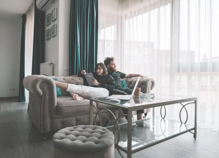 A young couple lounge on a sofa in a modern apartment interior